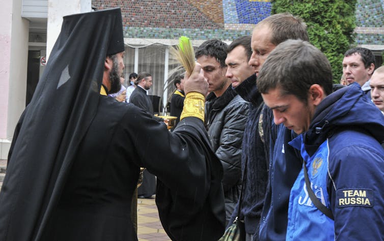 A Russian Orthodox priest blesses conscripted men during a farewell ceremony at the recruiting office in Bataysk, Rostov region, Russia, 26 September 2022.