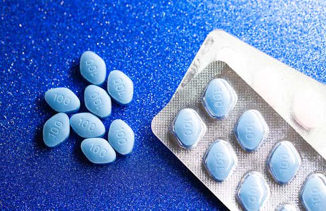 Blue diamond-shaped tablets in a blister pack and loose on a blue background