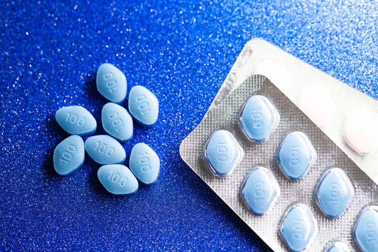Blue diamond-shaped tablets in a blister pack and loose on a blue background