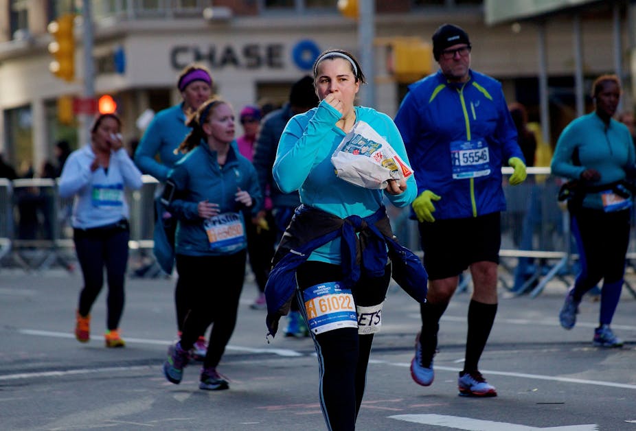 A woman eats a snack while running a marathon.