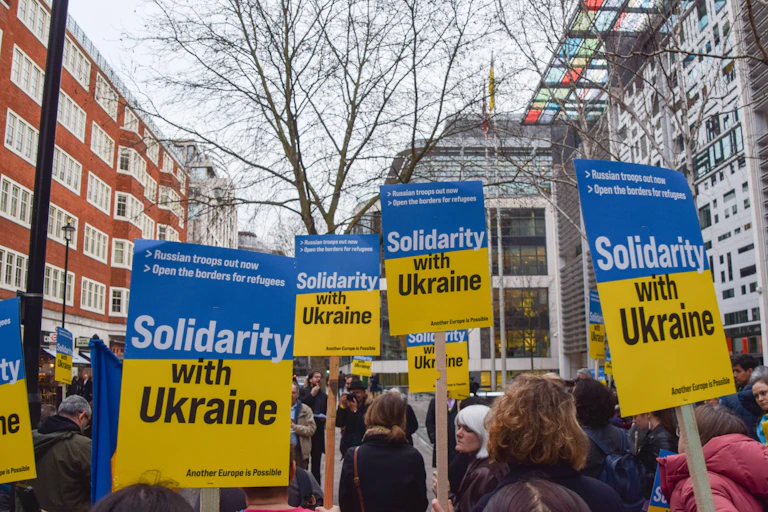 Protestors hold up yellow and blue posters in a street demonstration.