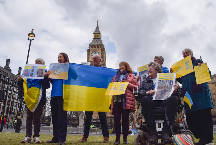 People with flags and handwritten posters in a city centre.