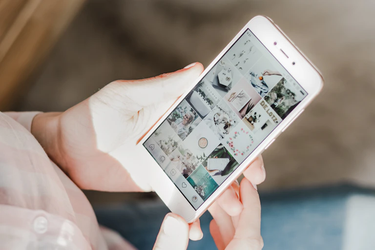 Hands holding a white smartphone displaying images on the screen.