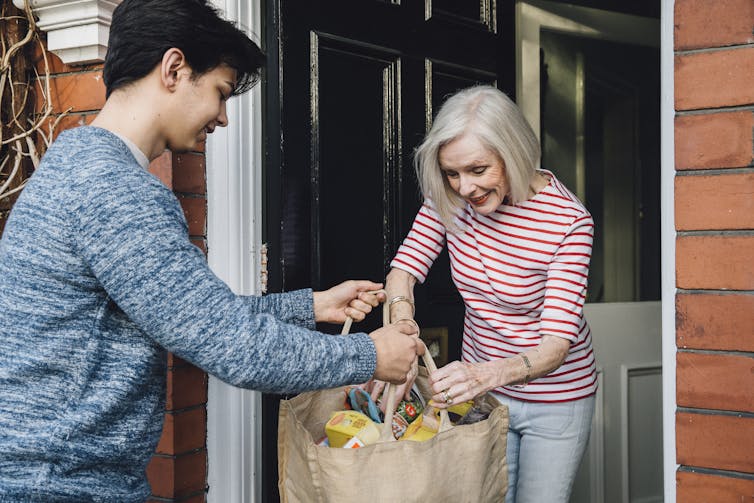 A young man delivering groceries to an older woman
