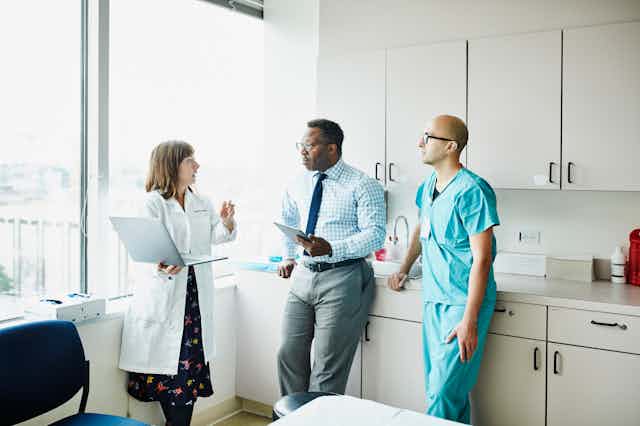 Three health care providers discussing in an exam room
