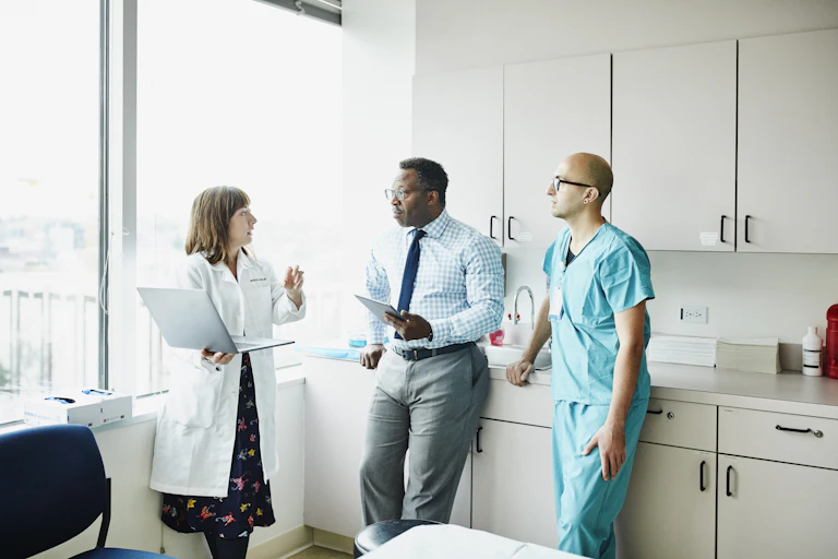 Three health care providers discussing in an exam room