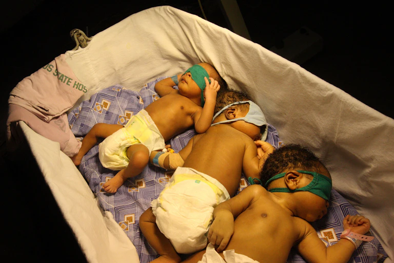 Young babies sleep together under a heat lamp at the Lagos Island Maternity Hospital, Lagos, Nigeria