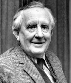 A man smiles in a shirt and tie in a black and white photo.
