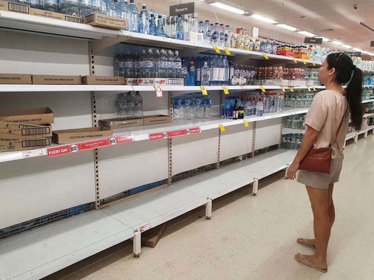 Woman looking at empty supermarket shelf