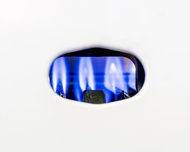 A luz piloto azul dentro de uma caldeira a gás branca.
