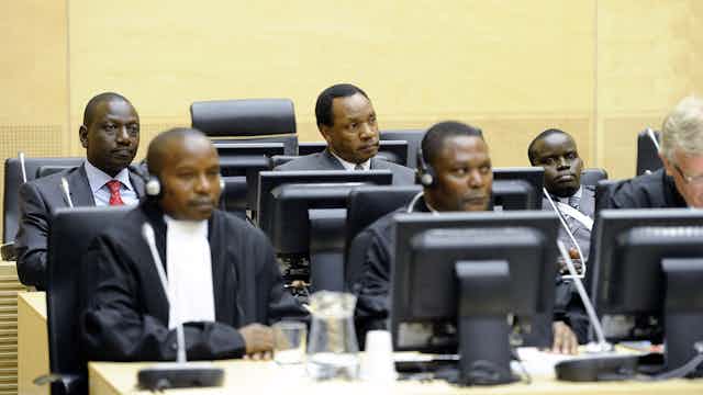 Three Kenyans being charged in connection with electoral violence sit in a criminal court 