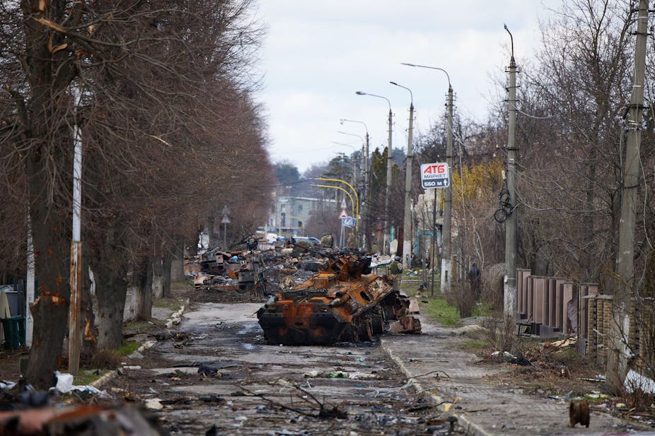 Remains of tanks in a tree-lined streets.
