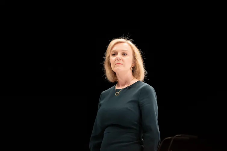 Liz Truss against a black background looking worried