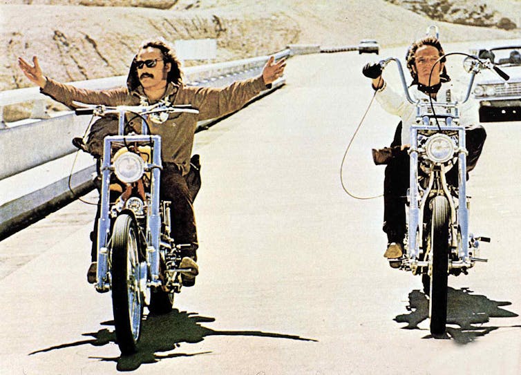 Two men ride motorcycles on the highway.