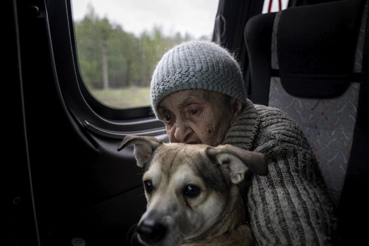 An elderly woman sits on her bus with a dog with a grey muzzle.
