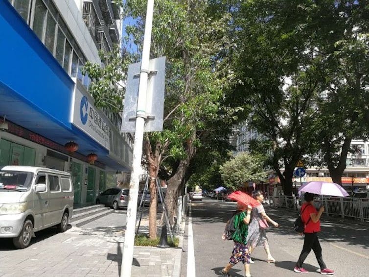 A street scene in Shenzen showing vehicles parked on footpaths and pedestrians using informal crosswalks.
