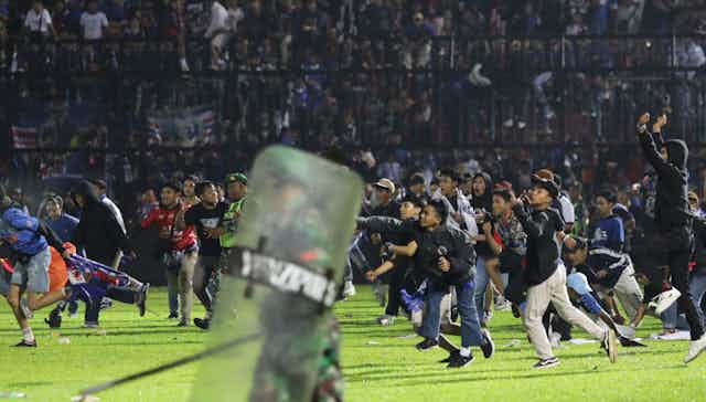 Spectators at a soccer match storm the field, with police among them