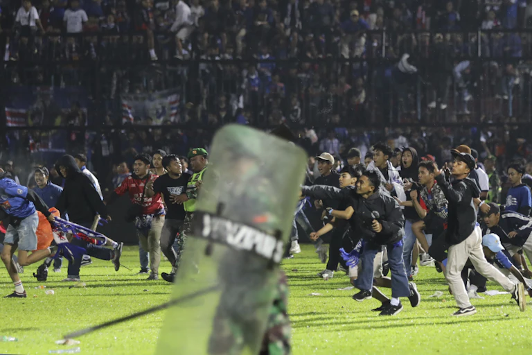 Spectators at a soccer match storm the field, with police among them