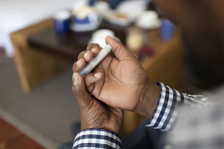 Close up man pricks finger for diabetes blood test