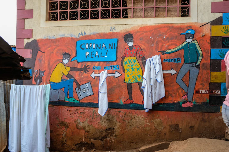 A mural on a wall showing COVID-19 social distancing guidelines, with a speech bubble written, 'Corona ni real'