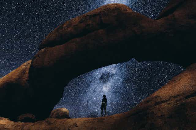 Silhouette of woman exploring there Spitzkoppe scenic landscape during the night full of stars and Milky Way