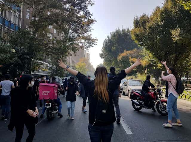 A woman withuot a hijab holds her amrs up while protesting in Tehran against compulsory headscarves following the death of a 22-year-old woman, Mahsa Amini in police custody for not wearing the veil.