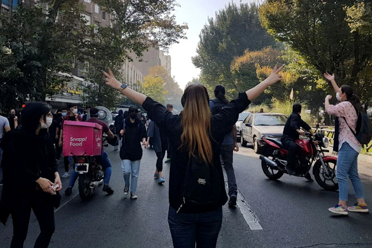 A woman withuot a hijab holds her amrs up while protesting in Tehran against compulsory headscarves following the death of a 22-year-old woman, Mahsa Amini in police custody for not wearing the veil.