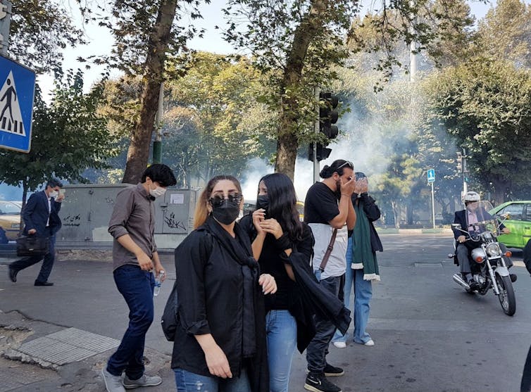 A group of young protesters flee tear gas in Theran, October 2022.