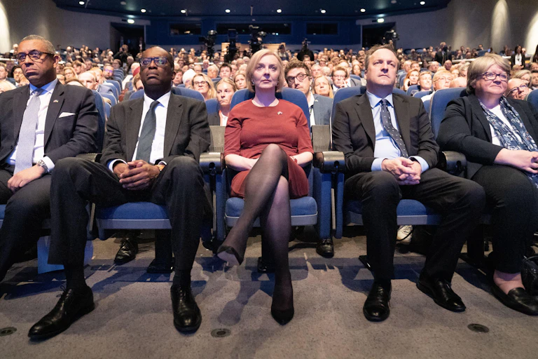 James Cleverly, Kwasi Kwarteng, Liz Truss, Hugh O'Leary and Thérèse Coffey sitting in a row in an audience, all looking glum.