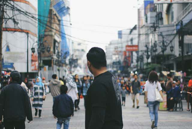 homme regardant au loin vers une rue bondée