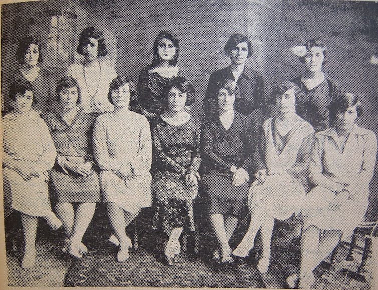 A black and white photograph shows two dozen women formally posed in two rows.