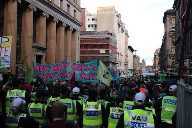 A protest in Glasgow with a sign that reads 'how many COPs to arrest climate chaos'