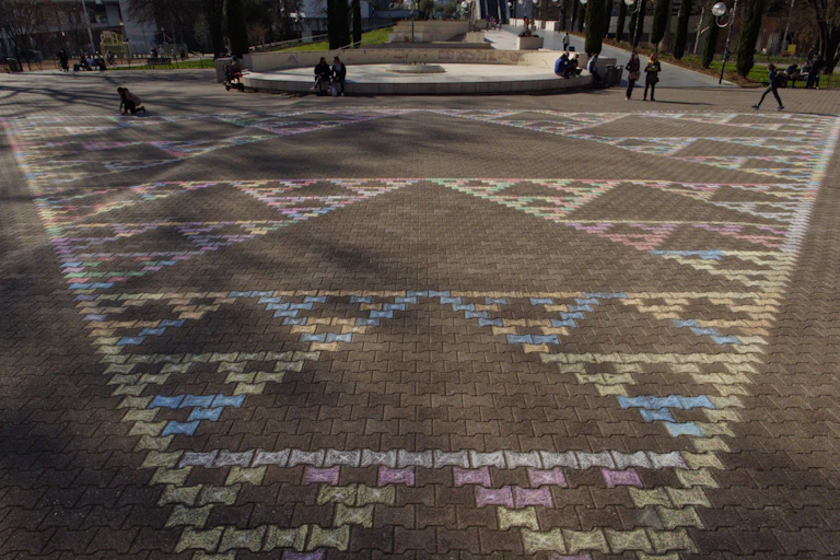 Un triangle plein de trous, dit triangle de Sierpiński, dessiné à la craie sur la place Carnot à Lyon.