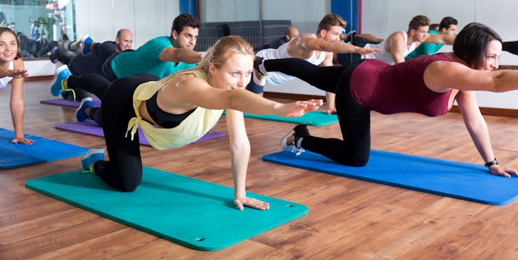A group of young people perform the same pose during a yoga class.