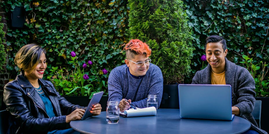 Students seen around a table against foliage.