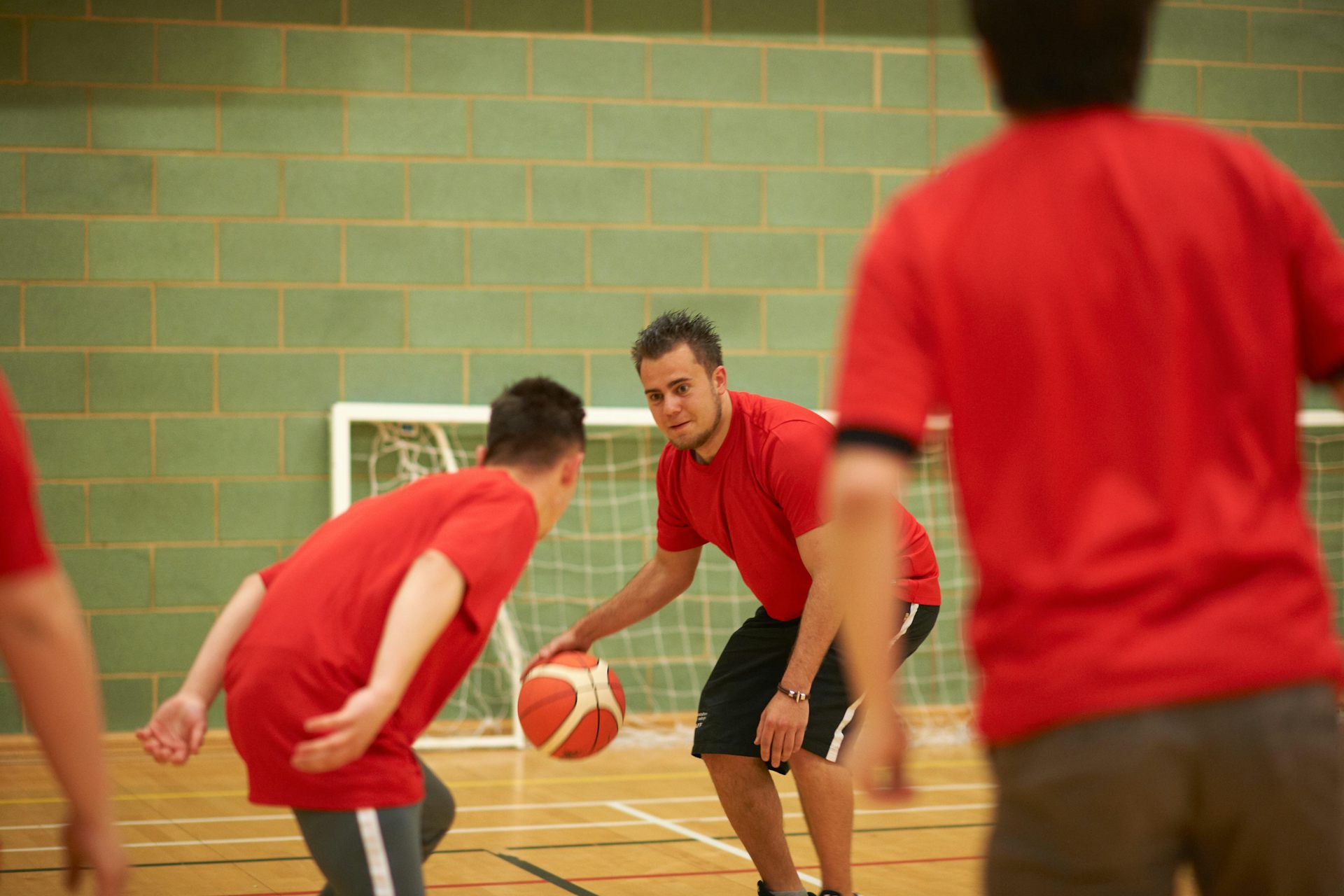 A group of young men in red T-shirts playing basketball.