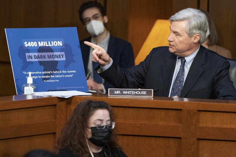 A senator points to an infographic with a quote from a Washington Post article about how a conservative activist raised millions of dollars to promote conservative judges and causes