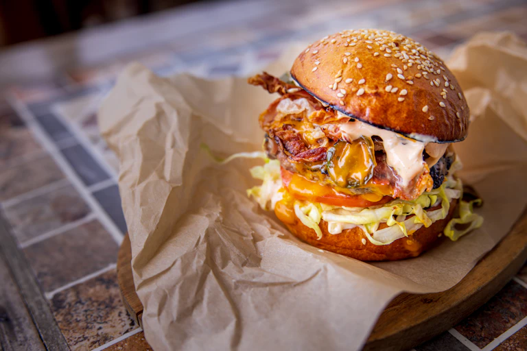 A very large bacon cheeseburger, dripping mayo, on a bun.