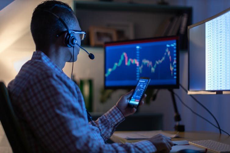 Man in dark looking at trading screens