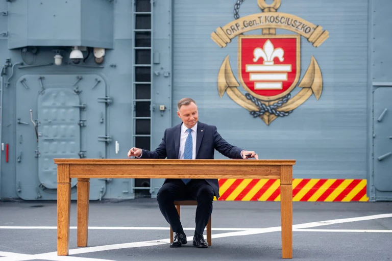 Andrzej Duda assis à une table sur un navire de guerre