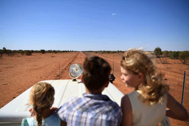 Three kids in a car, looking at drought-hit land