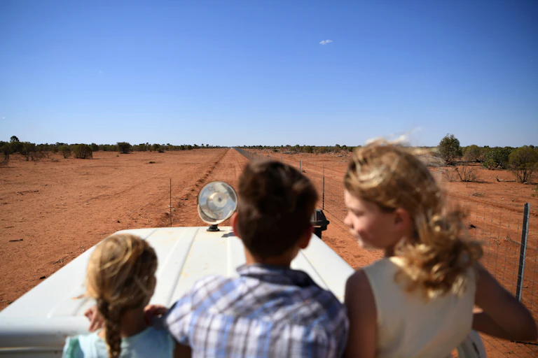Three kids in a car, looking at drought-hit land
