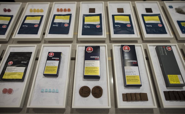 A display of candies, cookies and chocolate squares, each displayed with its black packaging with yellow and white warning labels.