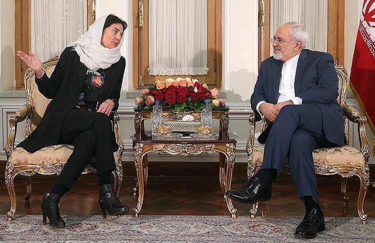 : Woman wearing a white headscarf sits next to a man in a suit.