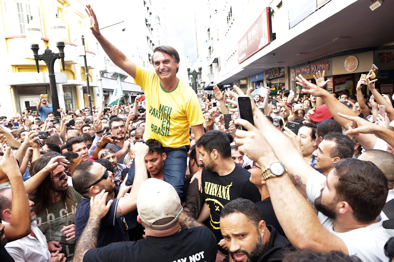 A man in a yellow t-shirt with his arm up.