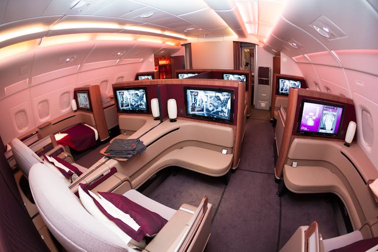 Large sofas and TV screens in the first-class section of an aeroplane.