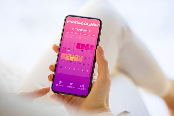 A woman uses a period tracking app on her phone.