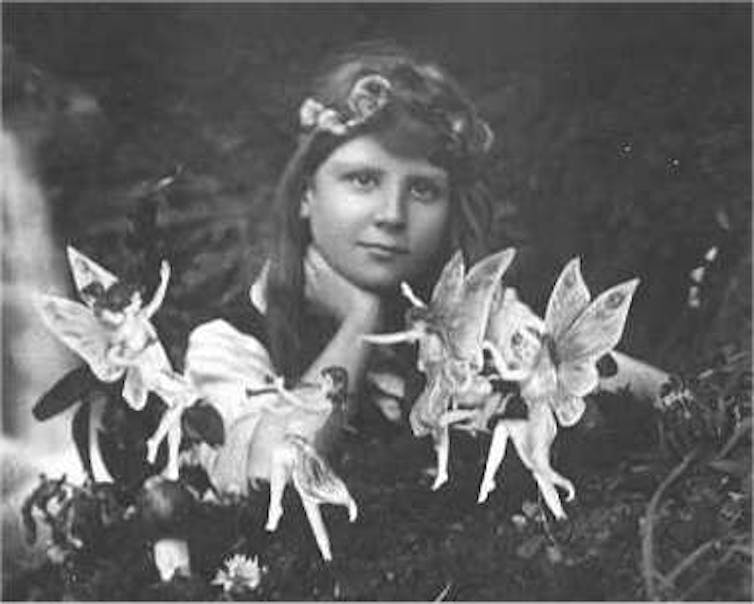 Black and white image of a girl surrounded by paper cutouts of fairies