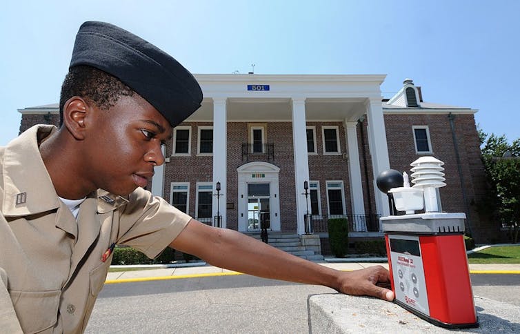 Technicien militaire vérifiant un thermomètre-globe mouillé, qui permet d’anticiper les situations de stress thermique, sur la base navale de Corry, en Floride