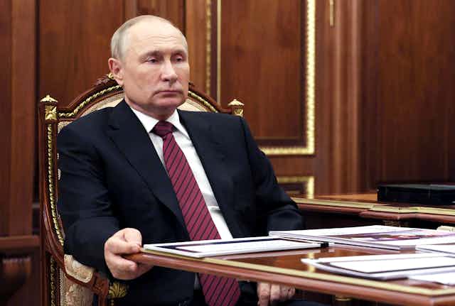 Vladimir Poutine assis devant une table